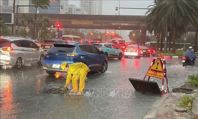 Công nhân Công ty TNHH MTV Thoát nước Hà Nội khẩn trương ứng trực kịp thời tiêu thoát nước trên đường Dương Đình Nghệ. (Ảnh: Nguyễn Thắng/TTXVN)