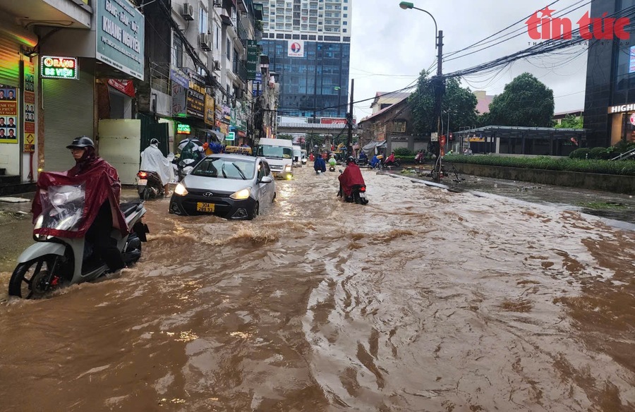 Nước ngập sâu tới 50cm trên đường Nguyễn Tuân, khiến nhiều phương tiện giao thông bị chết máy, người dân phải bì bõm lội nước (Ảnh TTXVN)