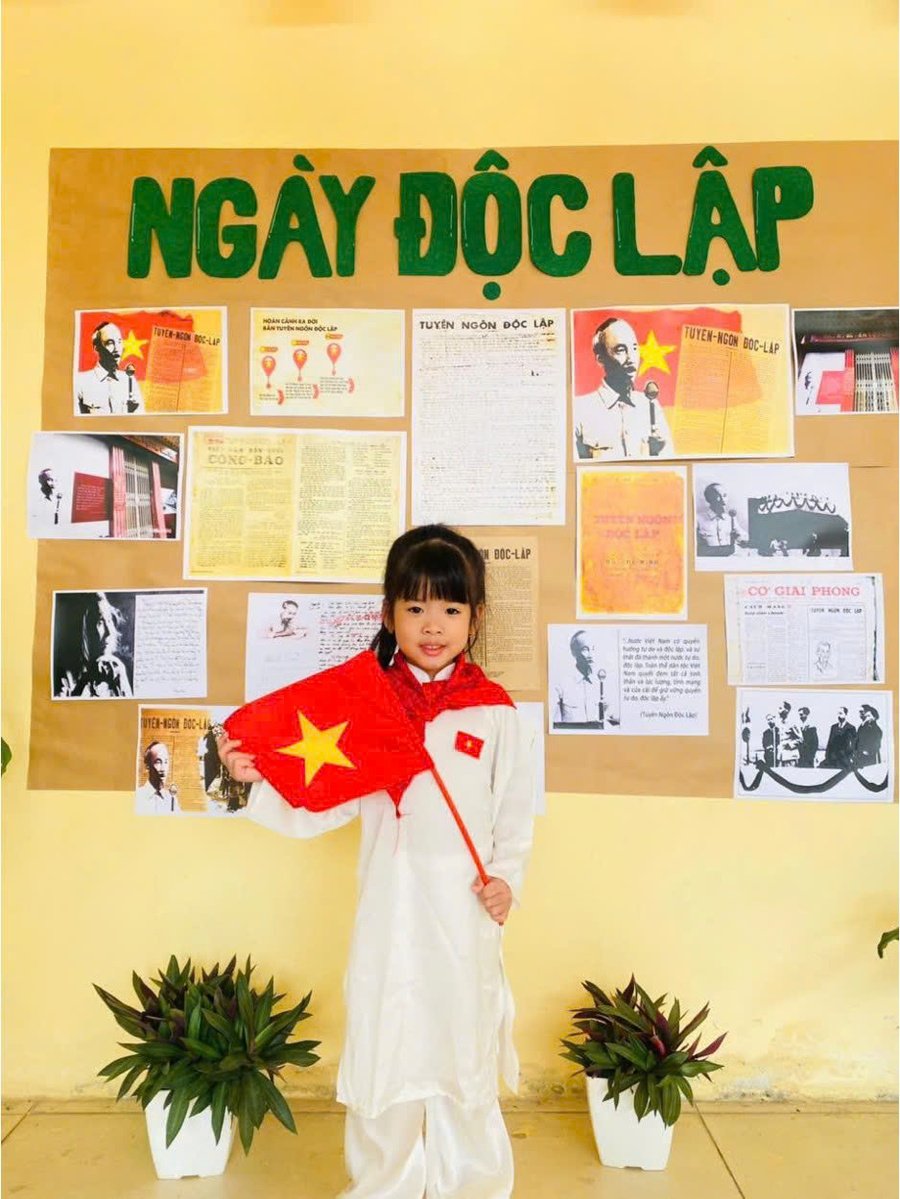 Các bé Trường mầm non Hoa Mai trong trang phục trắng tinh khôi, tay cầm cờ đỏ sao vàng tham gia hoạt động kỷ niệm Ngày Độc Lập