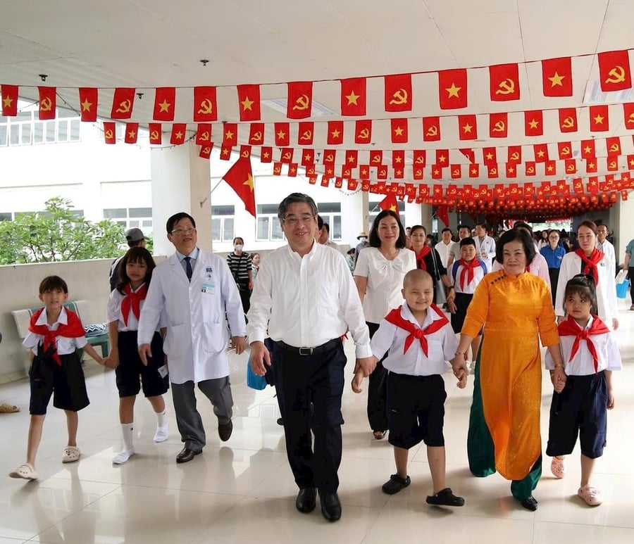 Ông Nguyễn Phước Lộc dắt tay các bệnh nhi vào lớp học sau lễ khai giảng