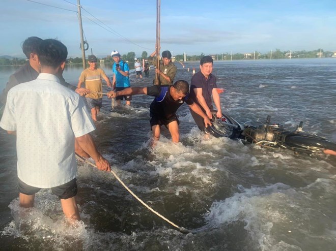 Người dân và lực lượng chức năng kịp thời ứng cứu 2 vợ chồng cùng phương tiện bị nước cuốn. Ảnh: Người dân cung cấp (LĐO)