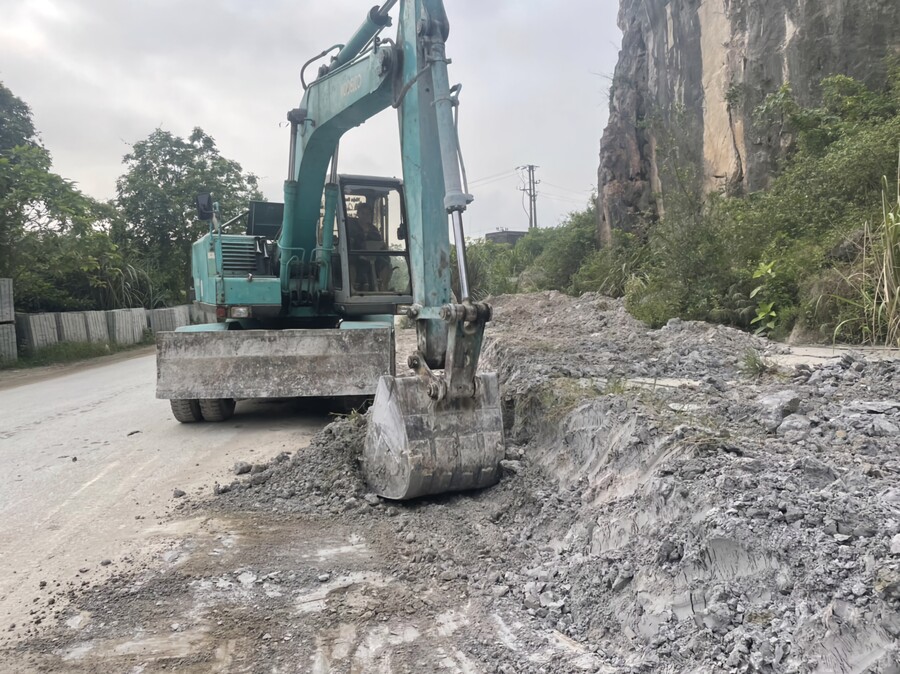 Máy múc thu gom, xử lý khu vực bột đá thải tràn ra Quốc lộ 47