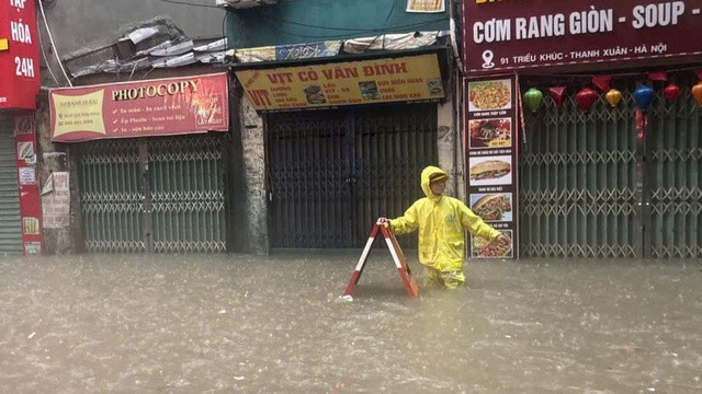 rận mưa lớn từ đêm qua khiến sáng nay nhiều tuyến đường bị ngập sâu, nhân viên thoát nước phải dưng biển cảnh báo (Ảnh: VGP/TL)