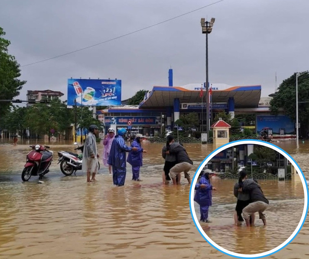 Người chồng đang đỡ đẻ cho vợ giữa dòng nước lũ. Ảnh: Hoàng Tất Thắng