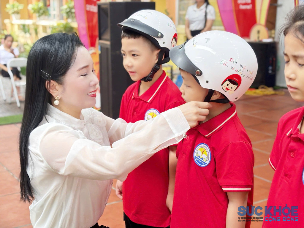 Nhà giáo Ưu tú Trần Thị Ánh Nguyệt đội mũ bảo hiểm cho các em học sinh 