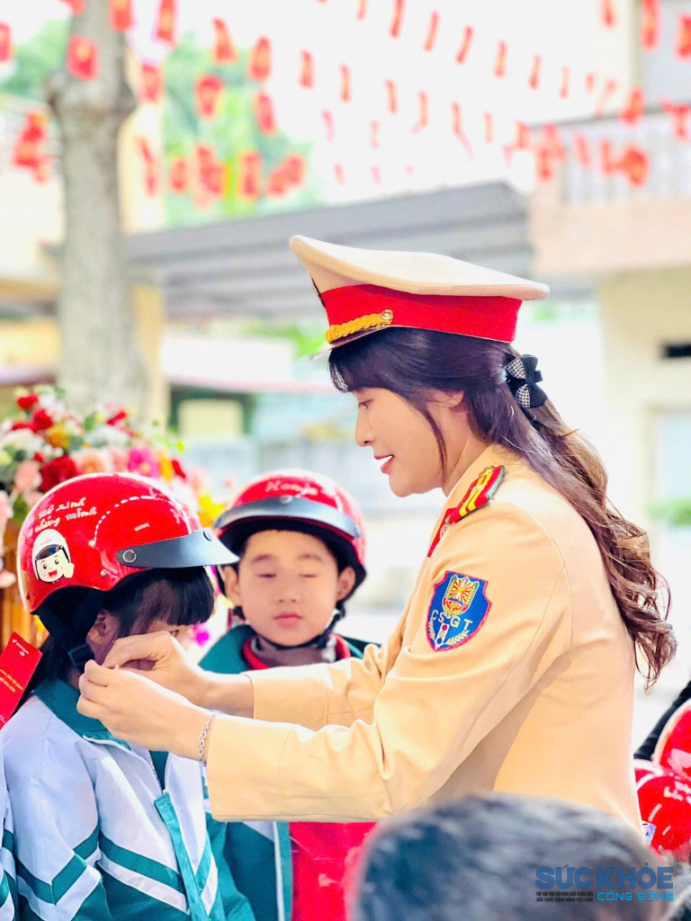 cán bộ cảnh sát giao thông hướng dẫn học sinh đội mũ bảo hiểm khi tham gia giao thông( ảnh PV)
