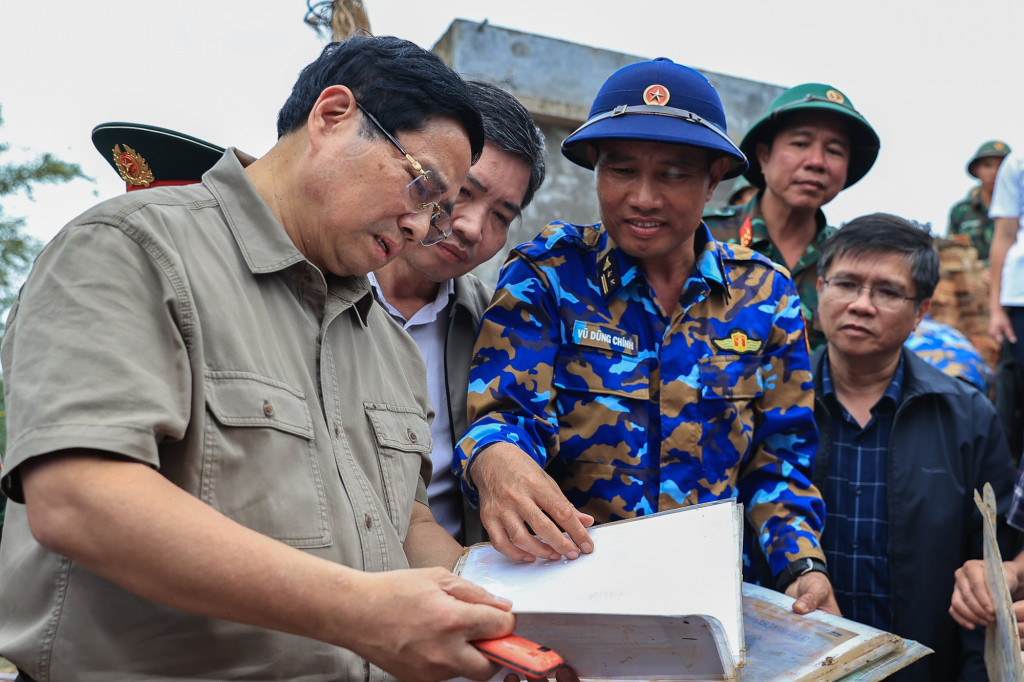 Thủ tướng xúc động xem những vật dụng của người dân còn sót lại sau lũ lụt tại xã Hòa Thịnh (Ảnh: VGP)