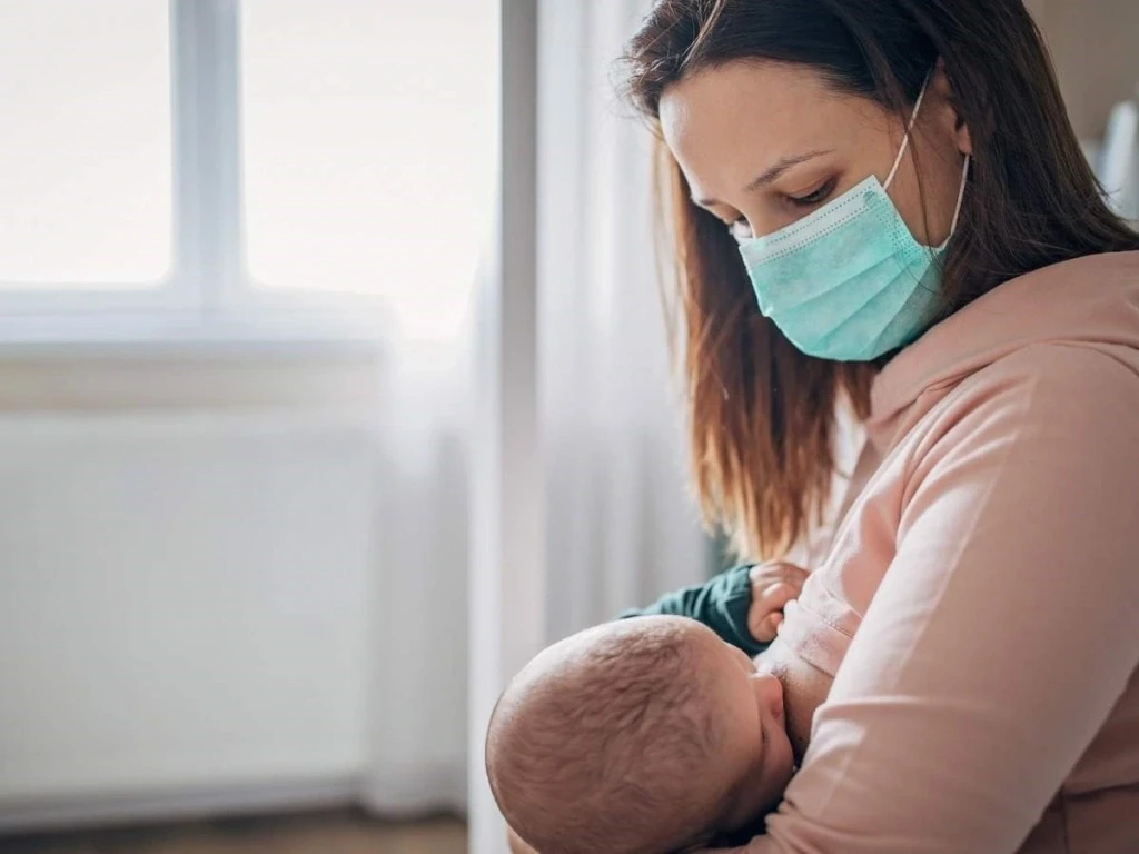 Mẹ bị cảm nên đeo khẩu trang khi cho con bú (Ảnh: Sưu tầm)