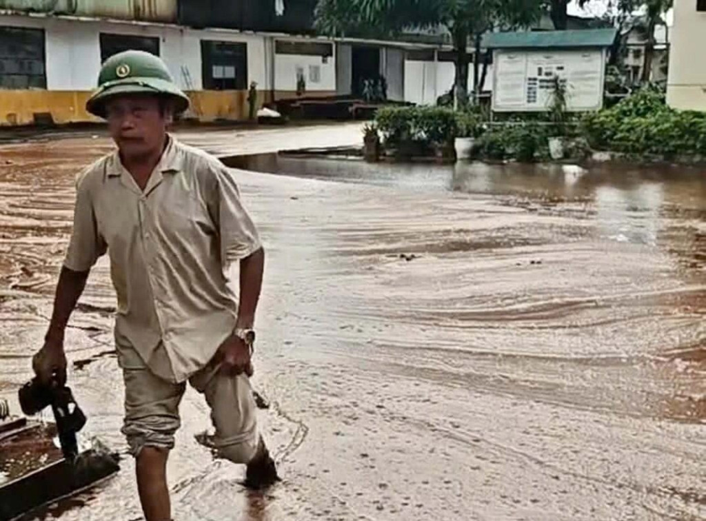 Một người lội trong dòng mật chảy tràn trên đường, sau khi bể chứa bị sét đánh (Ảnh: Người dân cung cấp)