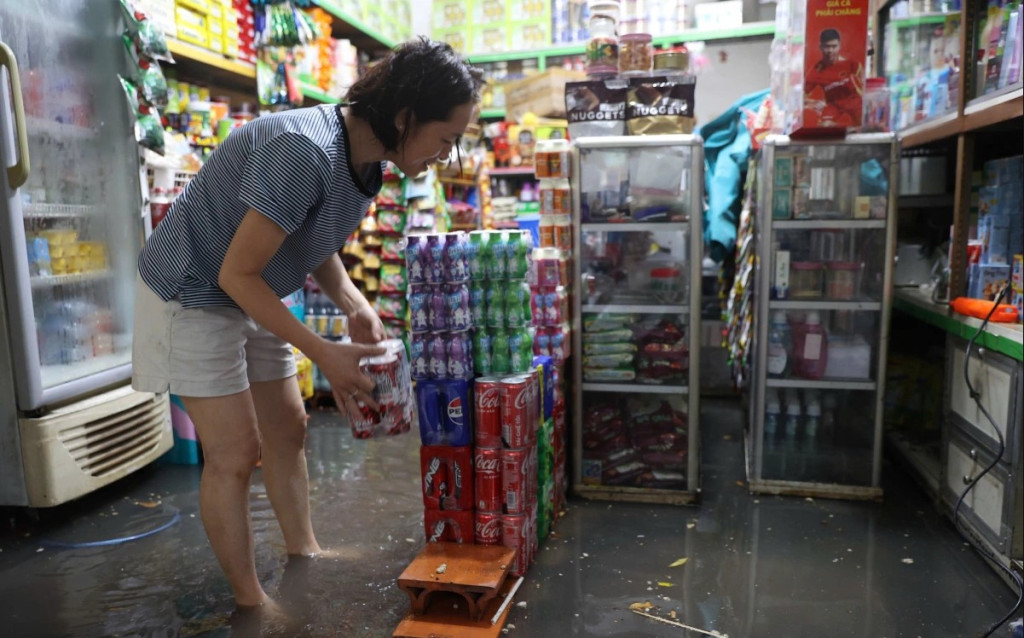 Bà Huỳnh Được (48 tuổi) kê cao hàng hóa để tránh ngập. Theo bà, đường Đặng Thị Rành vừa được nâng cấp dịp Tết nên nước rút nhanh hơn, song nhiều nhà thấp hơn mặt đường vẫn bị nước tràn vào.

