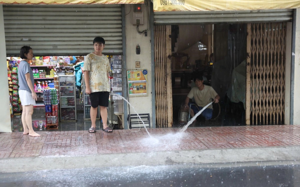 Nhiều hộ dân dùng máy bơm đưa nước từ trong nhà ra đường sau cơn mưa. 