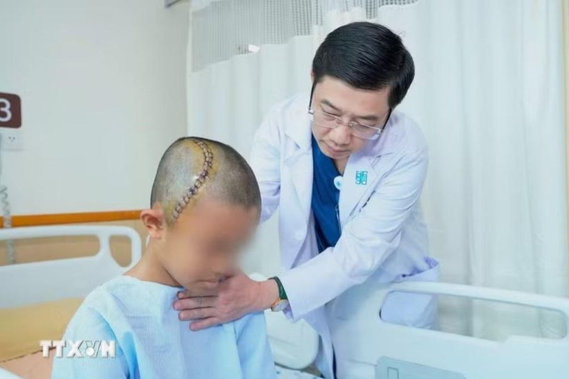 Tiến sỹ, bác sỹ Trương Thanh Tình, Trưởng Khoa Ngoại Thần kinh-Bệnh viện Đại học Y dược Thành phố Hồ Chí Minh thăm khám cho bệnh nhi sau phẫu thuật (Ảnh: TTXVN phát)