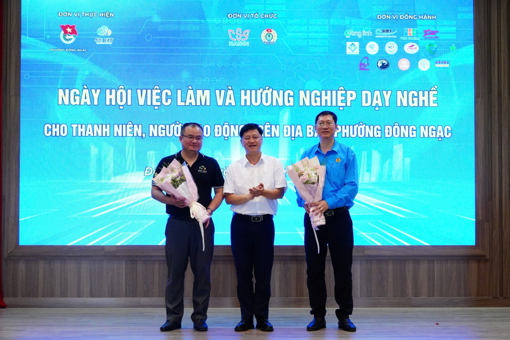Ông Lại Hồng Đăng (đứng giữa) – Phó Giám đốc phụ trách Trung tâm Dịch vụ việc làm và Hỗ trợ Thanh thiếu niên Hà Nội tặng hoa tri ân các đơn vị phối hợp tổ chức và thực hiện chương trình gồm Công đoàn phường Đông Ngạc (bên phải) và Công ty Cổ phần Truyền thông Nhị Vân (bên trái) ( Ảnh Nguyễn Phương) 