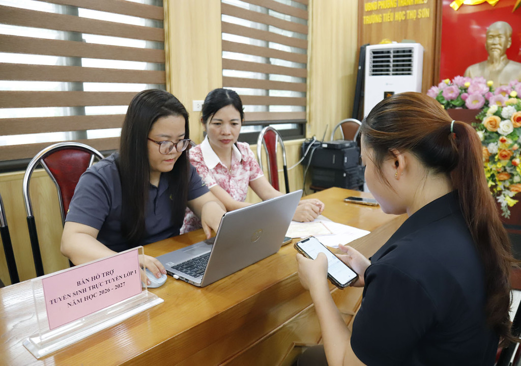 Cán bộ, giáo viên Trường Tiểu học Thọ Sơn hướng dẫn phụ huynh thực hiện đăng ký tuyển sinh đầu cấp trực tuyến (ảnh: Đình Thơm)